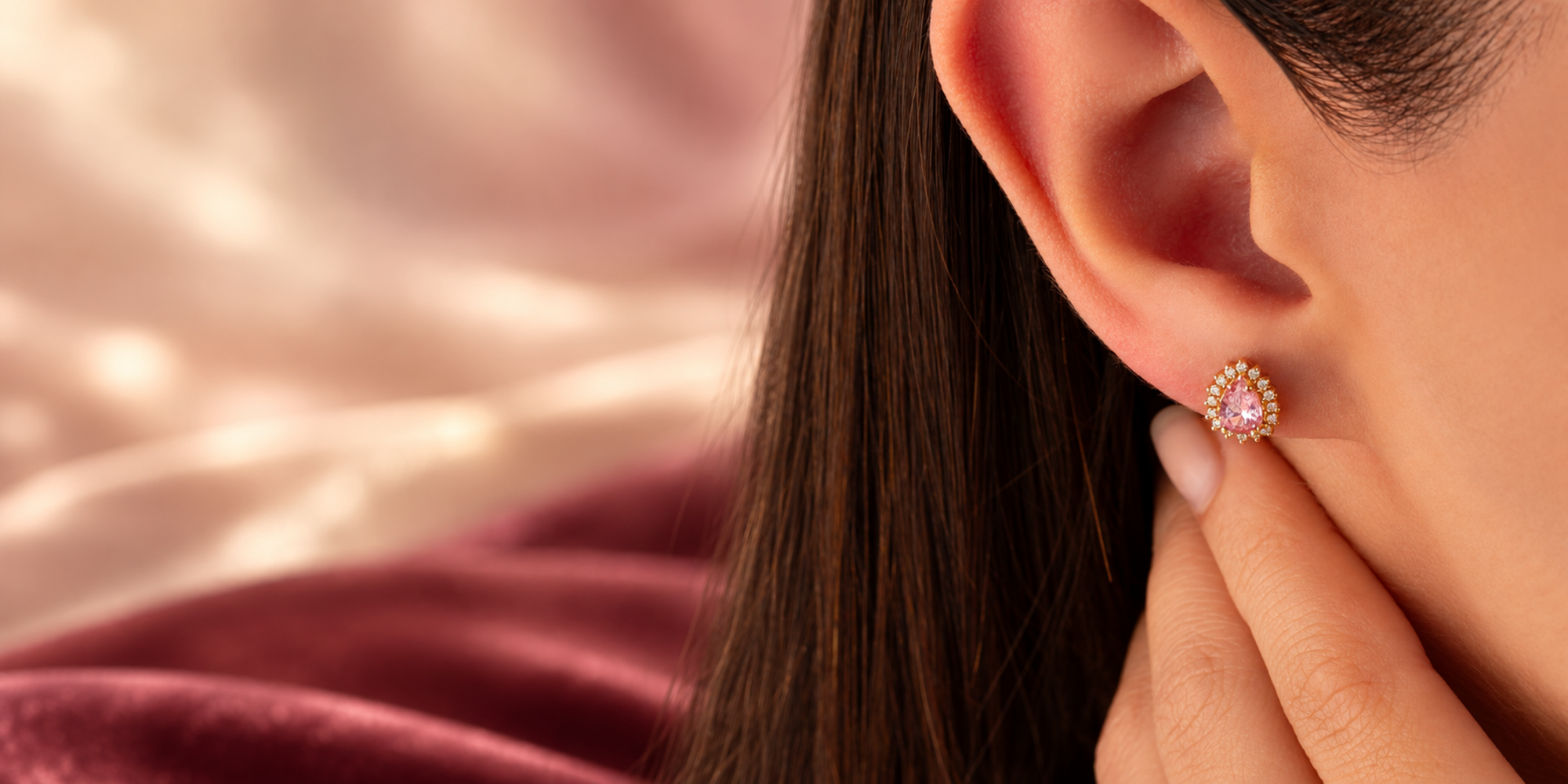 Woman wearing a teardrop Pink Tourmaline and diamond halo stud earring in solid gold